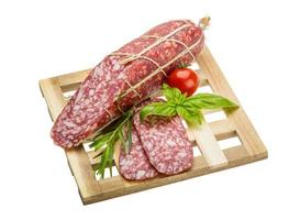 salame na placa de madeira e fundo branco foto