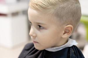 close-up de menino com novo penteado na barbearia. foto