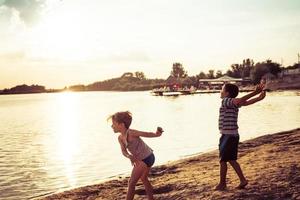 meninos brincalhões se divertindo na praia ao pôr do sol. foto