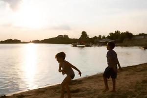 crianças despreocupadas brincando na praia e se divertindo ao pôr do sol. foto