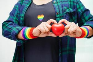 mulher asiática segurando hert vermelho com bandeira do arco-íris, direitos do símbolo lgbt e igualdade de gênero, mês do orgulho lgbt em junho. foto