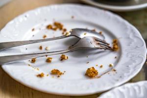 prato sujo vazio com colher e garfo na mesa depois do café da manhã foto