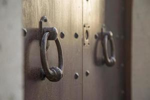 portas de madeira velhas com anéis e alça de aldrava de aço vintage antiquado close-up na itália. foto