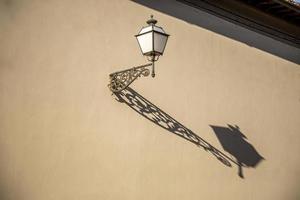 lâmpada elétrica à moda antiga com uma longa sombra montada na fachada histórica na itália. foto