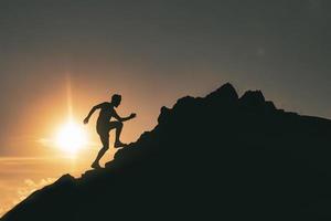 um homem corre entre as rochas em um pôr do sol colorido da montanha foto