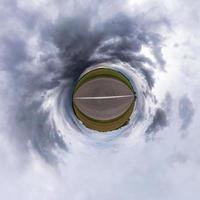 pequena transformação do planeta do panorama esférico 360 graus. vista aérea abstrata esférica em campo com céu de tempestade e lindas nuvens escuras impressionantes. curvatura do espaço. foto