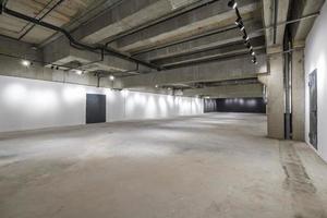 interior vazio da grande sala de concreto como armazém ou hangar com holofotes foto
