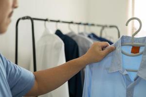 homem está escolhendo a camisa no quarto de roupas em casa. foto