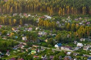 vista panorâmica aérea da aldeia verde com casas, celeiros e estrada de cascalho na floresta foto