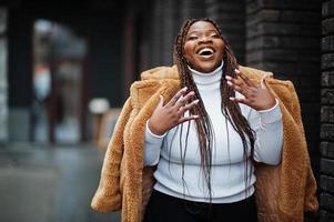 glamourosa mulher afro-americana em pose de casaco de pele quente na rua. foto