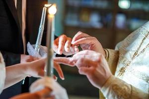 o padre ajuda os noivos a trocar alianças na cerimônia de casamento na igreja foto