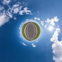 pequeno planeta na estrada de asfalto no céu azul com sol e belas nuvens. transformação do panorama esférico 360 graus. vista aérea abstrata esférica. curvatura do espaço. foto