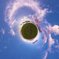 pequeno planeta no céu azul com sol e belas nuvens. transformação do panorama esférico 360 graus. vista aérea abstrata esférica. curvatura do espaço. foto