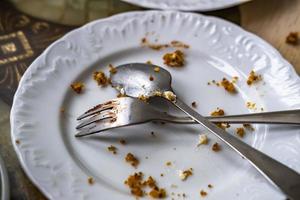 prato sujo vazio com colher e garfo na mesa depois do café da manhã foto