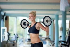 jovem no ginásio de fitness levantando pesos foto