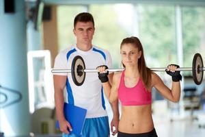 jovem mulher desportiva com levantamento de pesos de exercício de treinador foto