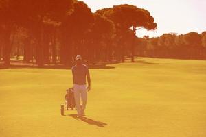 jogador de golfe andando com bolsa de rodas foto