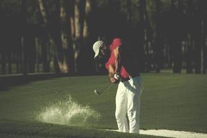 golfista acertando um bunker de areia foto