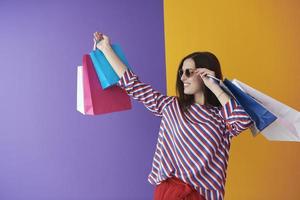 jovem mulher com sacolas de compras em fundo colorido foto