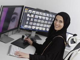designer gráfico feminino muçulmano trabalhando no computador usando tablet gráfico e dois monitores foto