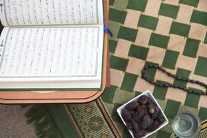 iftar tempo datas secas alcorão sagrado copo de água e tasbih no tapete de oração ou sejadah foto