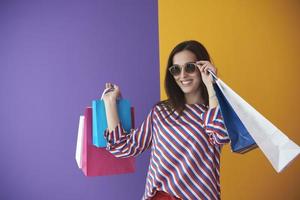 jovem mulher com sacolas de compras em fundo colorido foto