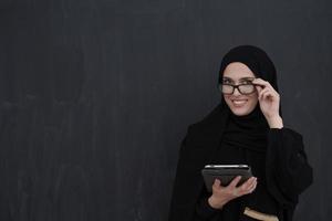 jovem empresária árabe em roupas tradicionais ou abaya segurando computador tablet foto