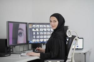 designer gráfico feminino muçulmano trabalhando no computador usando tablet gráfico e dois monitores foto