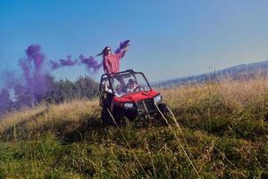 pessoas animadas se divertindo aproveitando um belo dia ensolarado segurando tochas coloridas enquanto dirigia um carro de buggy off road foto