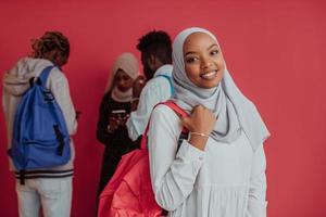 um grupo de estudantes muçulmanos africanos com mochilas posando em um fundo rosa. o conceito de educação escolar. foto