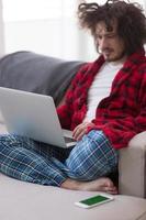 homem freelancer em roupão de banho trabalhando em casa foto