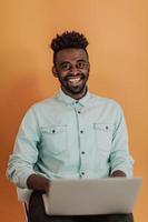 estudante africano usando laptop para estudar e fazer conexões de negócios fundo amarelo