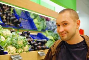 homem sorridente no supermercado foto