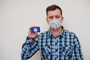 homem de camisa quadriculada mostra o cartão da bandeira de belize na mão, use máscara de proteção isolada no fundo branco. conceito de coronavírus de países americanos. foto