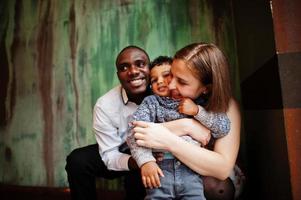 feliz família multiétnica com menino passa tempo no restaurante. relacionamentos de homem africano e mulher branca europeia. foto