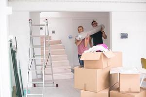 casal carregando um tapete se mudando para nova casa foto