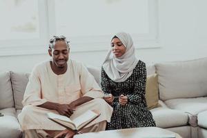 casal muçulmano africano em casa no Ramadã lendo o livro Alcorão Holly Islam. foto