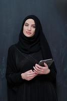 jovem empresária árabe em roupas tradicionais ou abaya com computador tablet foto