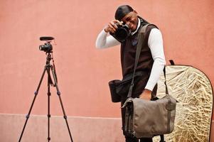 jovem cinegrafista americano africano profissional segurando câmera profissional com equipamento profissional. cinegrafista afro vestindo duraq preto fazendo vídeos. foto