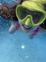 criança sorridente em óculos nadar, mergulhar na piscina com diversão - pular profundamente debaixo d'água. estilo de vida saudável, atividade de esportes aquáticos de pessoas nos verões. foto