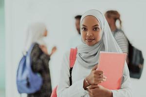 aluna africana com grupo de amigos em segundo plano vestindo roupas tradicionais de hijab islâmico. foco seletivo foto