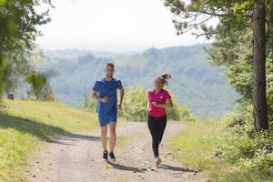 casal desfrutando de um estilo de vida saudável enquanto corre em uma estrada rural foto