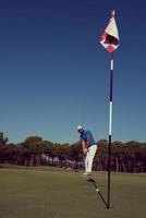 jogador de golfe acertando tiro em dia ensolarado foto