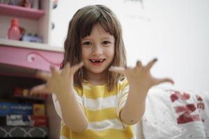 menina bonitinha em casa pintando com as mãos foto