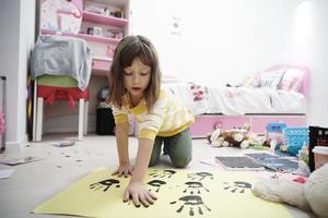 menina bonitinha em casa pintando com as mãos foto