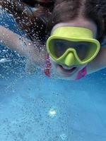 criança sorridente em óculos nadar, mergulhar na piscina com diversão - pular profundamente debaixo d'água. estilo de vida saudável, atividade de esportes aquáticos de pessoas nos verões. foto