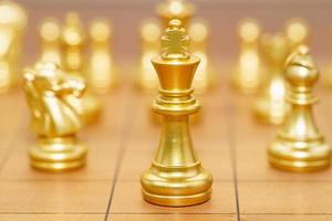 suporte de peça de xadrez rei de ouro no tabuleiro de xadrez de madeira foto