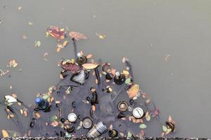 lixo e garrafa na água do canal. vista do topo foto