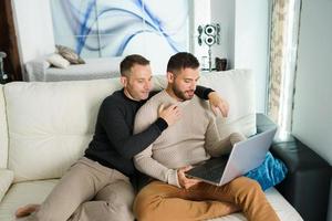 dois homens assistindo filme no laptop em casa foto