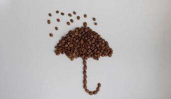 grãos de café em forma de guarda-chuva em um fundo cinza foto